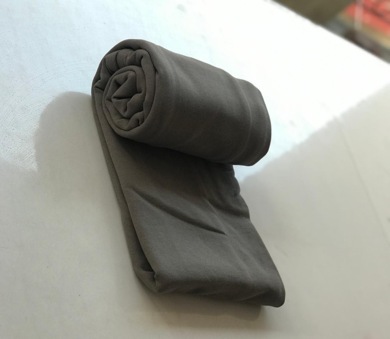 Rolled gray fabric or cloth on white surface with shadows.