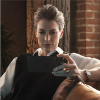 Woman on brown leather couch holding a tablet device.
