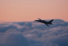 Jet plane with a camera flying above clouds at sunset