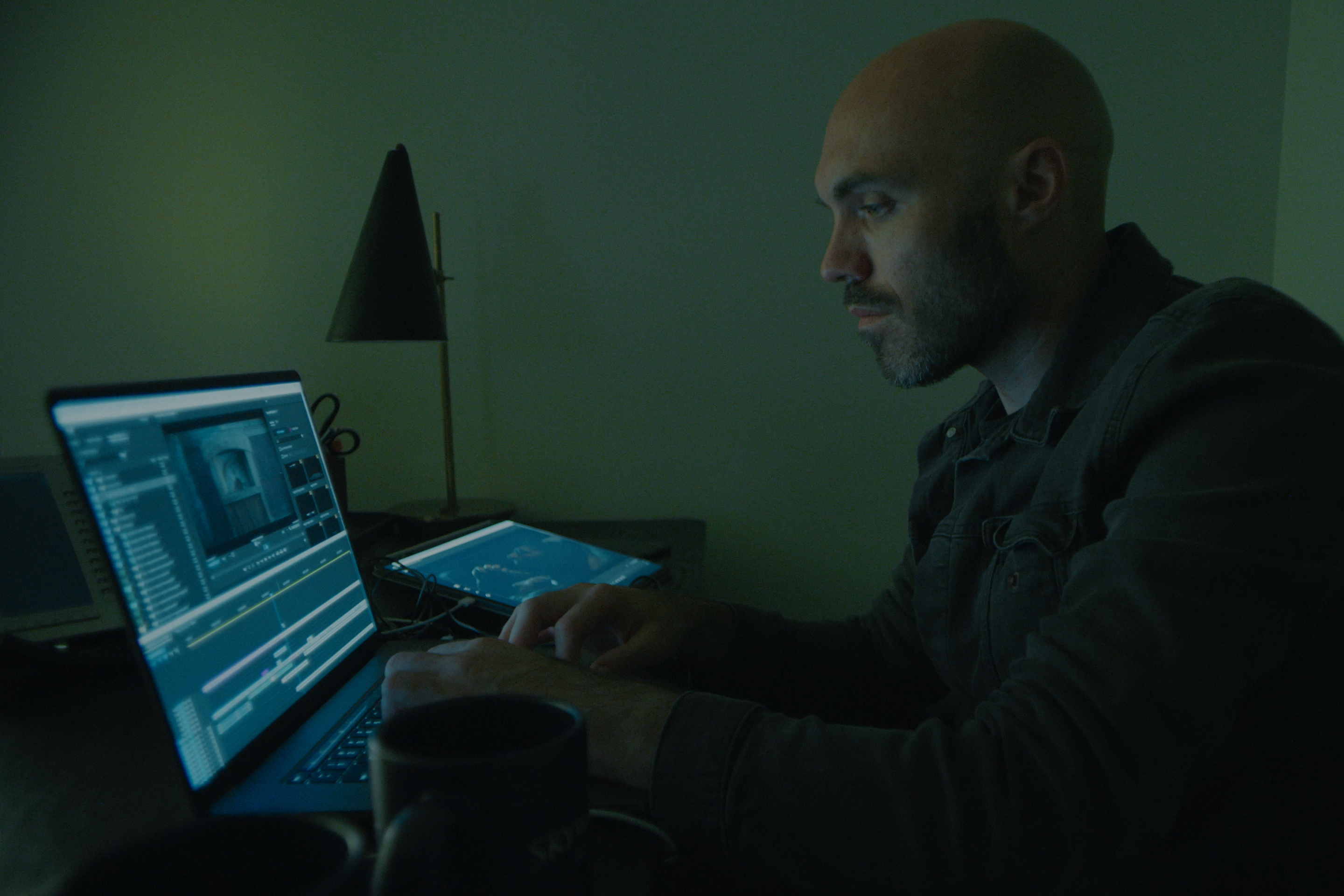 David Lowery, director of the movie The Green Knight, working on a laptop showing the Premiere Pro integration user interface.