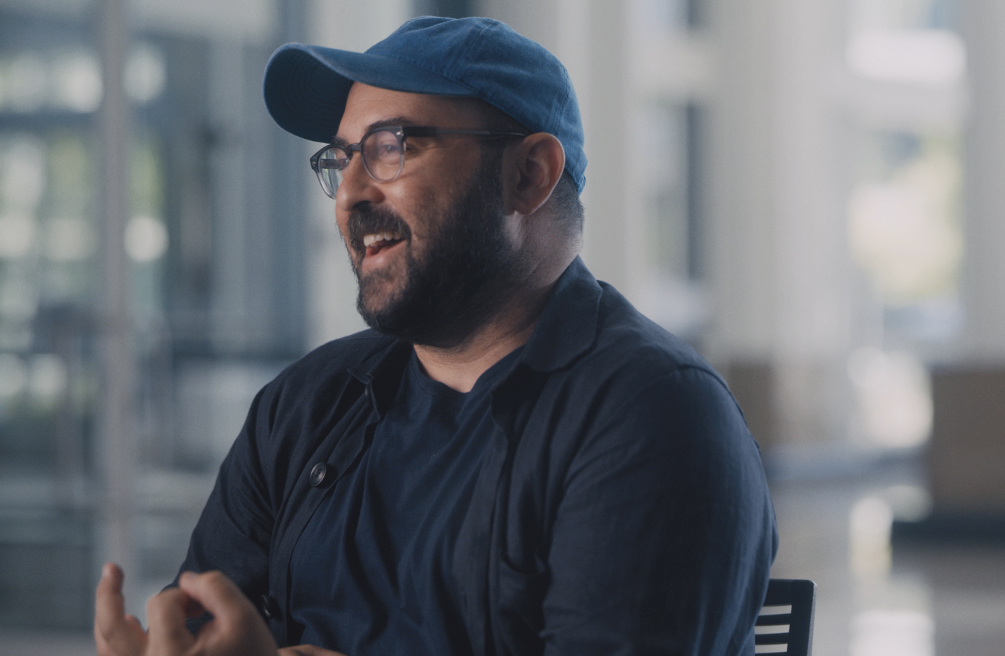 Man wearing baseball cap talking and gesticulating
