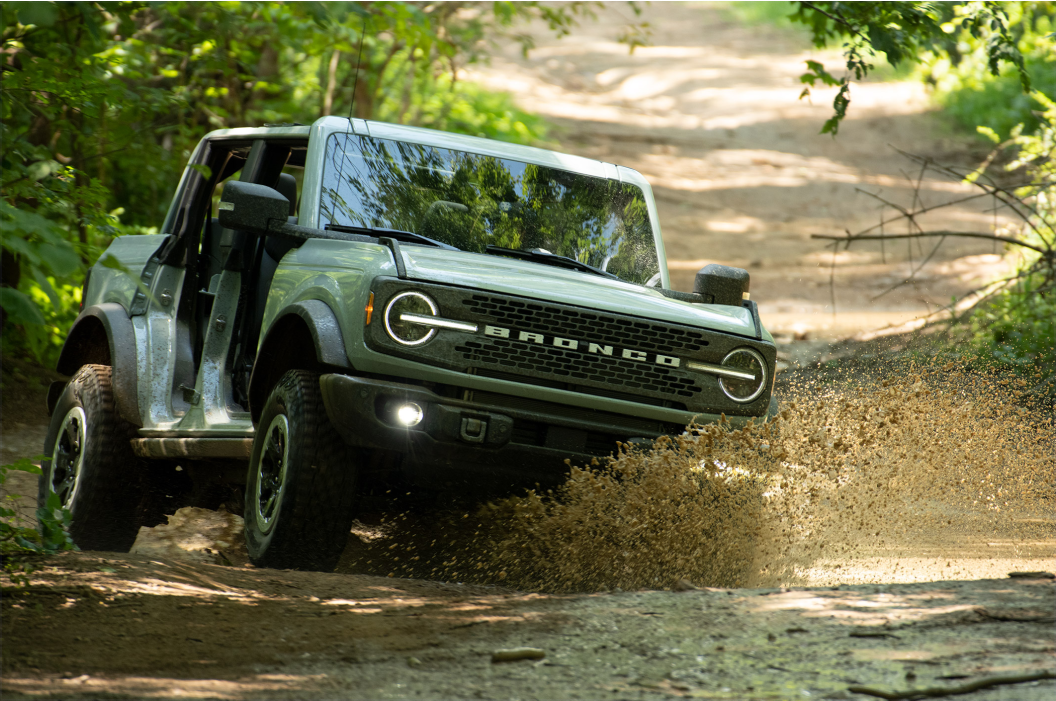 Ford bronco driving aggressively through mud.