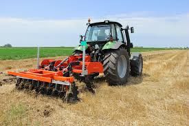 Lowery disc harrow breaking up soil behind a utility tractor