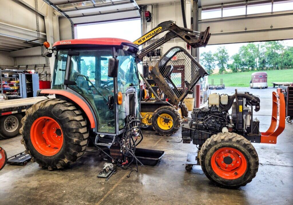 Technician servicing compact tractor in repair bay
