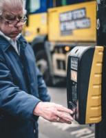 A man wearing glasses presses the button at a pedestrian crossing.