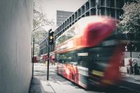 A bus with slight motion blur going through an amber light with Euston station seen in the background.