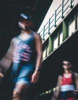 Two blurred figures of young men seen from a low angle walking under a bridge.