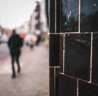 pub wall in foreground out of focus person walking in background.