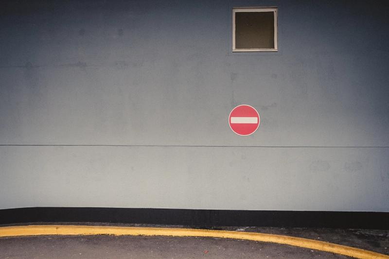 a no entry sign, a yellow curb a small grey window on a blue/grey wall. It's pretty dull tbh.