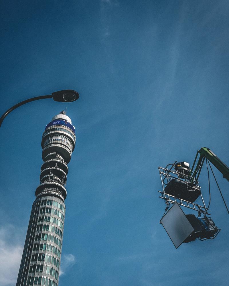 The BT Tower at a slight angle, with a street light apparently towering over it. TV camera lights on a crane are also visible on the opposite side of the frame.