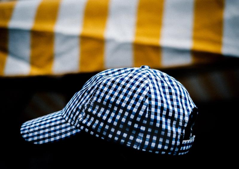 A plaid cap appears to be floating in front of a white and mustard striped awning.