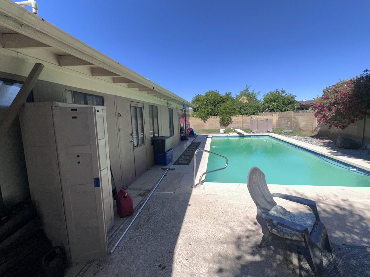 Before the remodel: the backyard pool and covered patio with bare concrete decking.