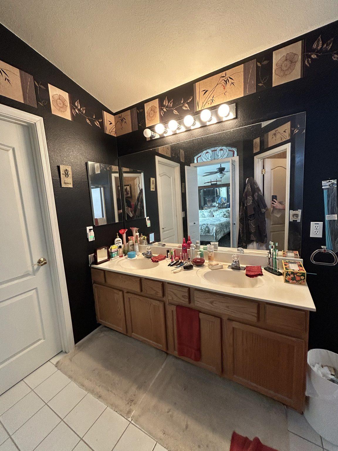 Before the remodel: the original primary bathroom vanity and mirrors, seen from the doorway.