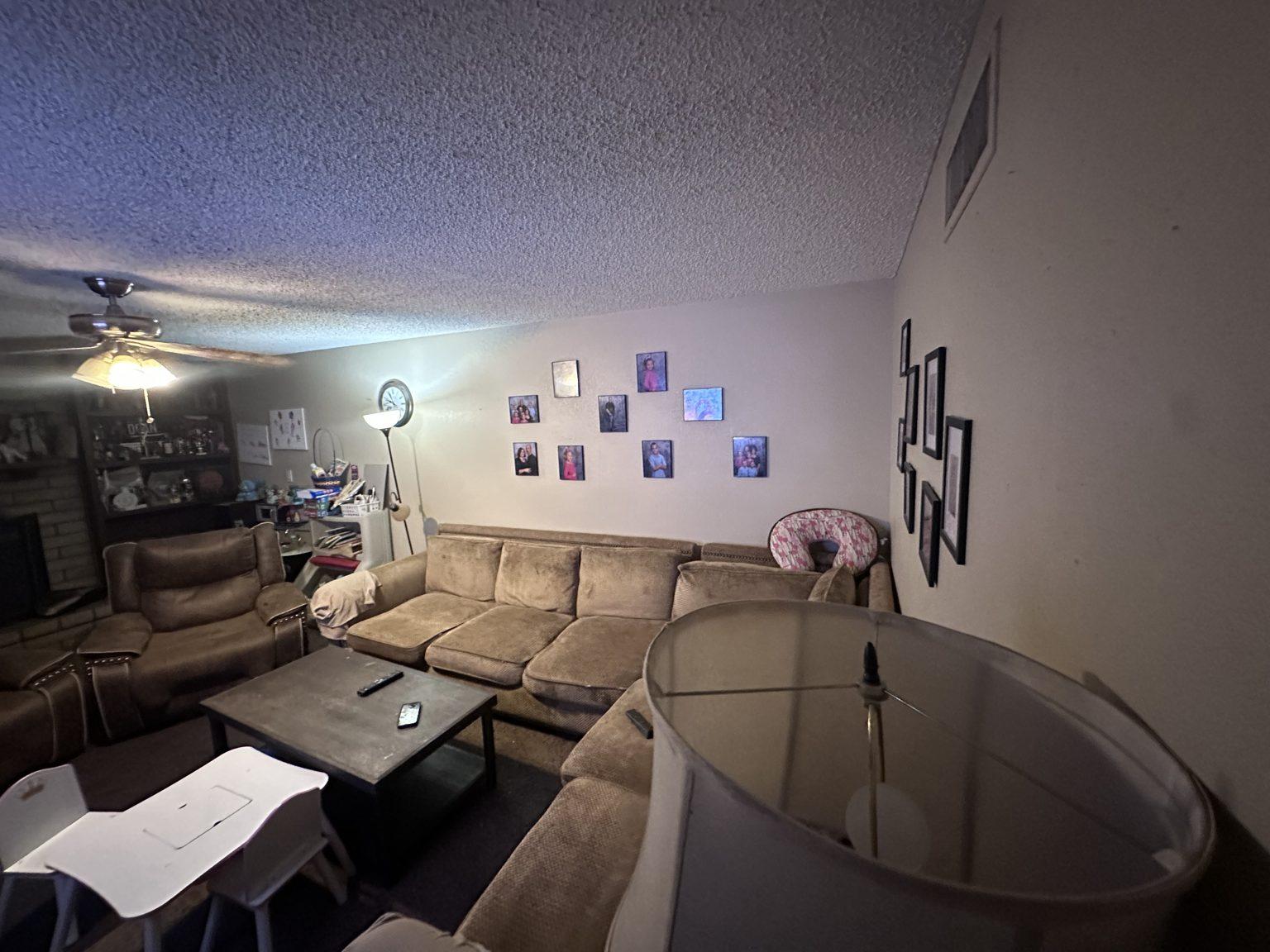 Before the remodel: the original living room with a brown sectional sofa and popcorn ceiling.