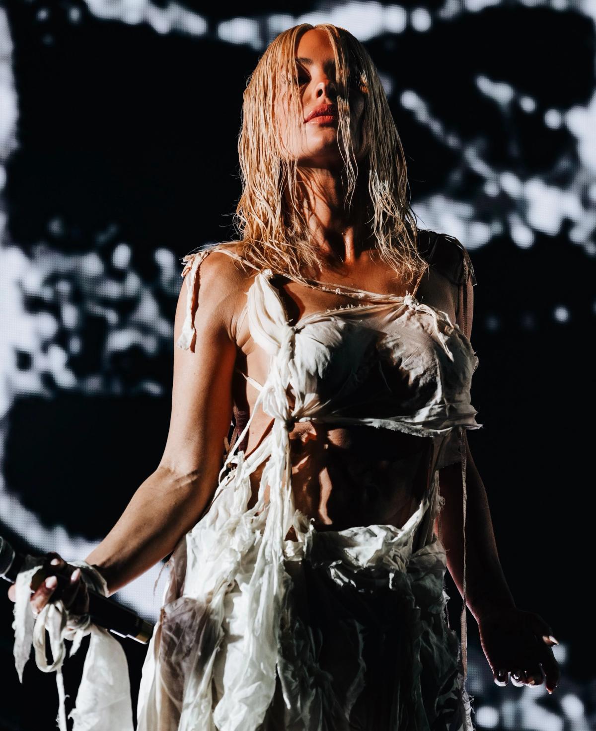 Aimée Sophia performing Dune on stage in a white dress