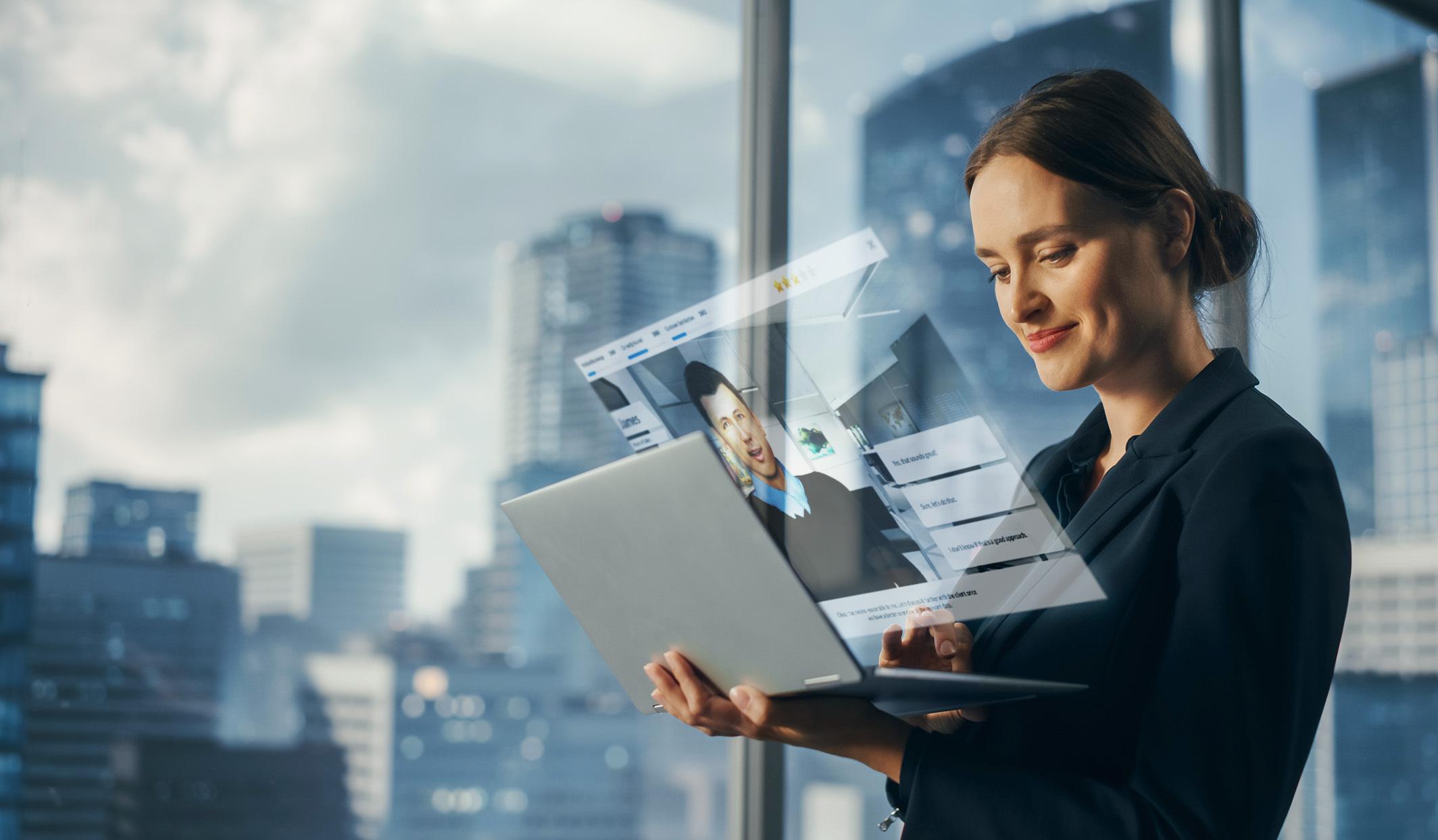 Smiling woman holds a laptop with a holographic video call in a modern office.
