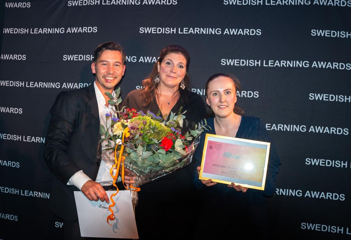 Drei lächelnde Personen mit Auszeichnungen und einem Blumenstrauß vor der Kulisse der Swedish Learning Awards