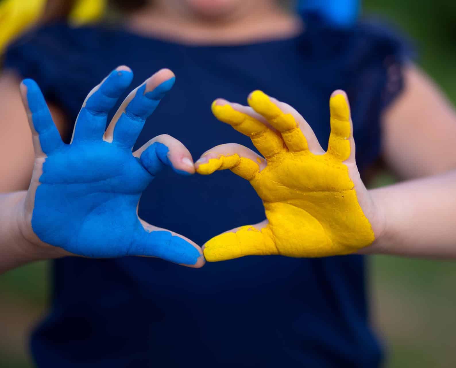 Kinderhände, blau und gelb bemalt, bilden ein Herz