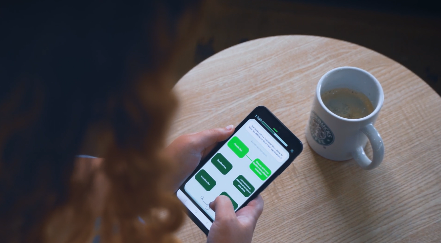 Hände beantworten in einem Attensi-Trainingsmodul auf dem Smartphone eine Multiple-Choice-Frage, daneben eine Starbucks-Tasse