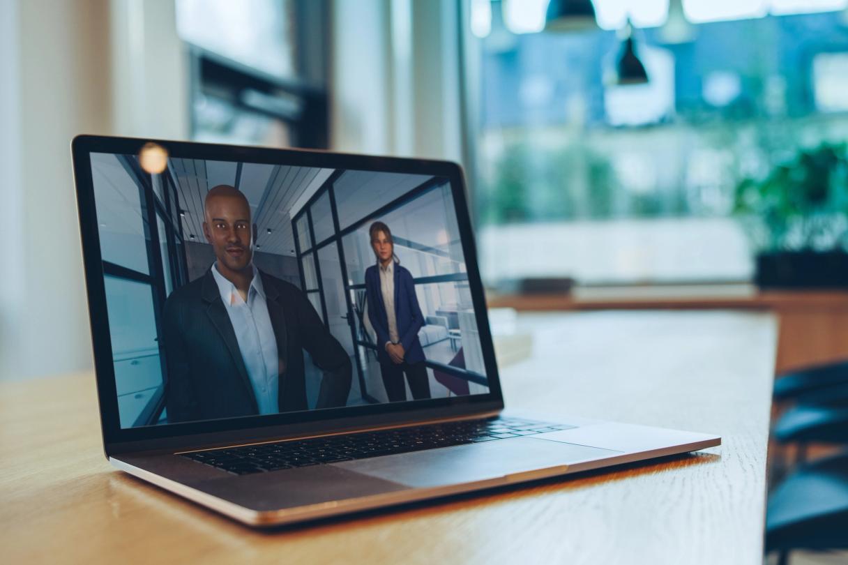 Bærbar PC på et trebord som viser to 3D-avatarer i en kontorsimulering