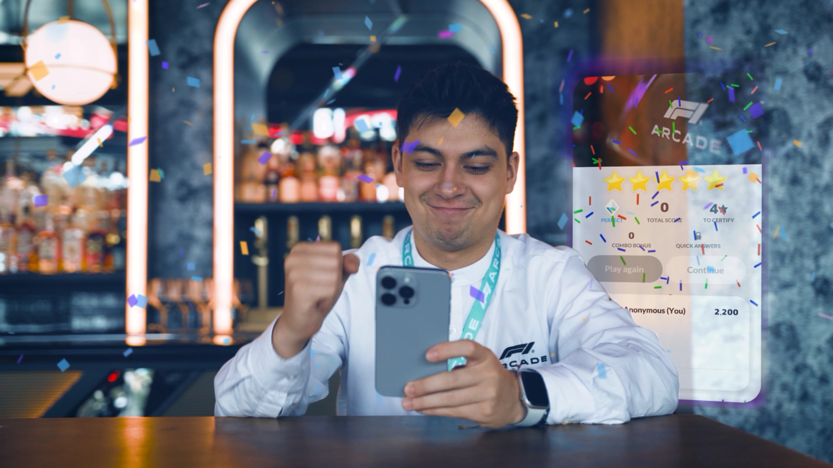 Ein Mann feiert auf seinem Smartphone einen Sieg im F1-Arcade-Spiel, während Konfetti fällt.