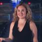 Erica Shertz smiling in a black top in a dimly lit studio space