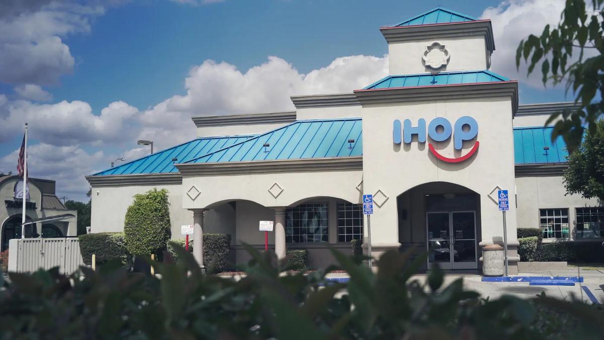 Außenansicht eines IHOP-Restaurants mit türkisem Dach und dem Markenschild über dem Bogeneingang