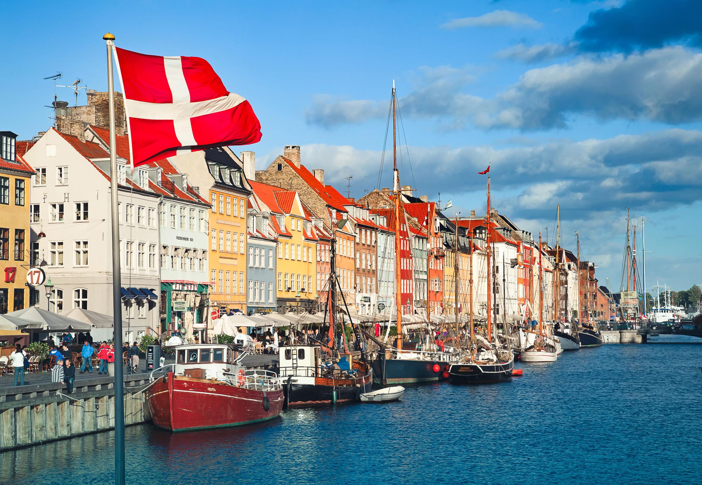 Le port de Nyhavn à Copenhague, avec ses maisons colorées, ses bateaux amarrés et un drapeau danois