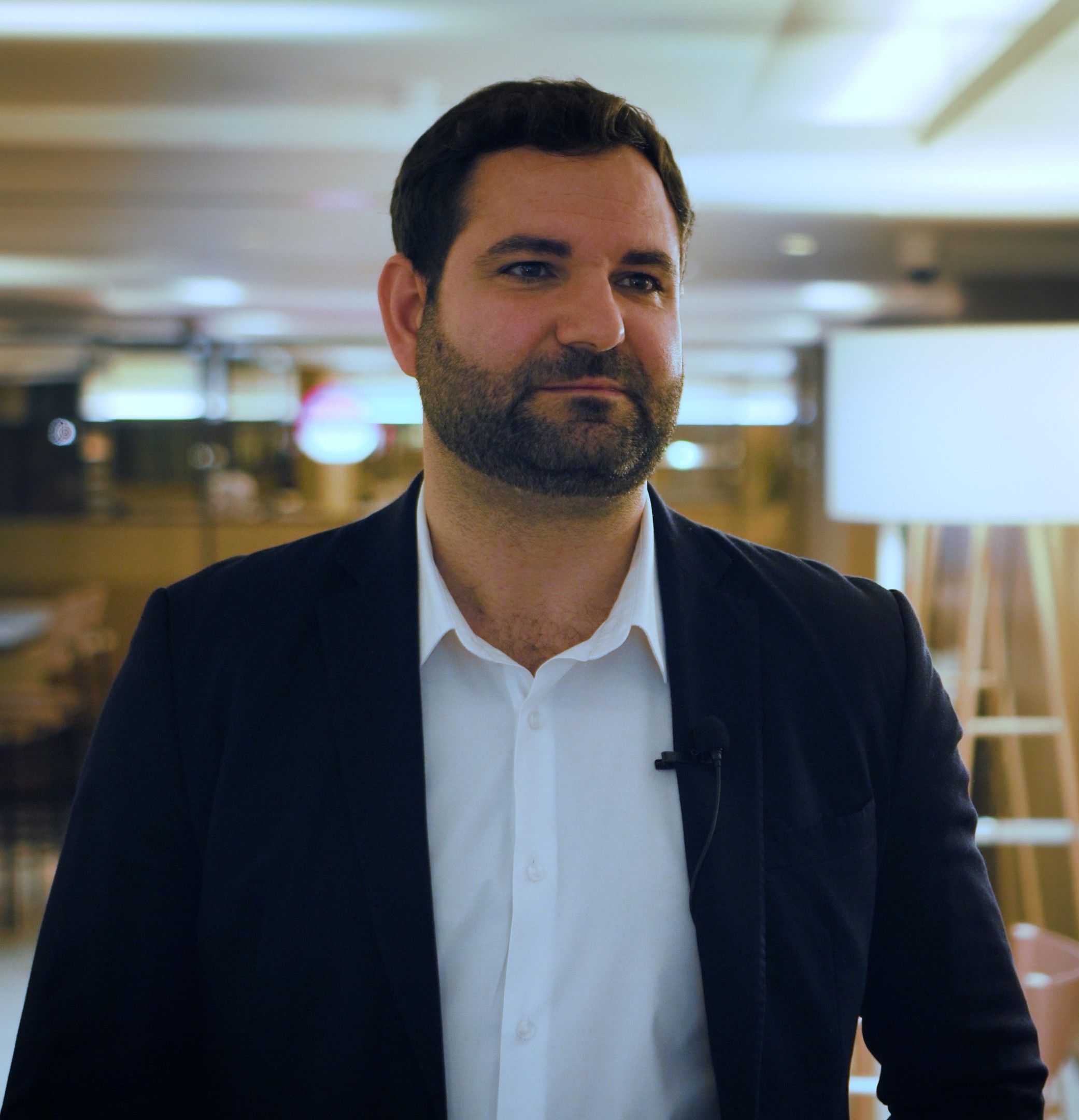 Pablo Torres lächelt während eines gefilmten Interviews in dunklem Blazer und weißem Hemd