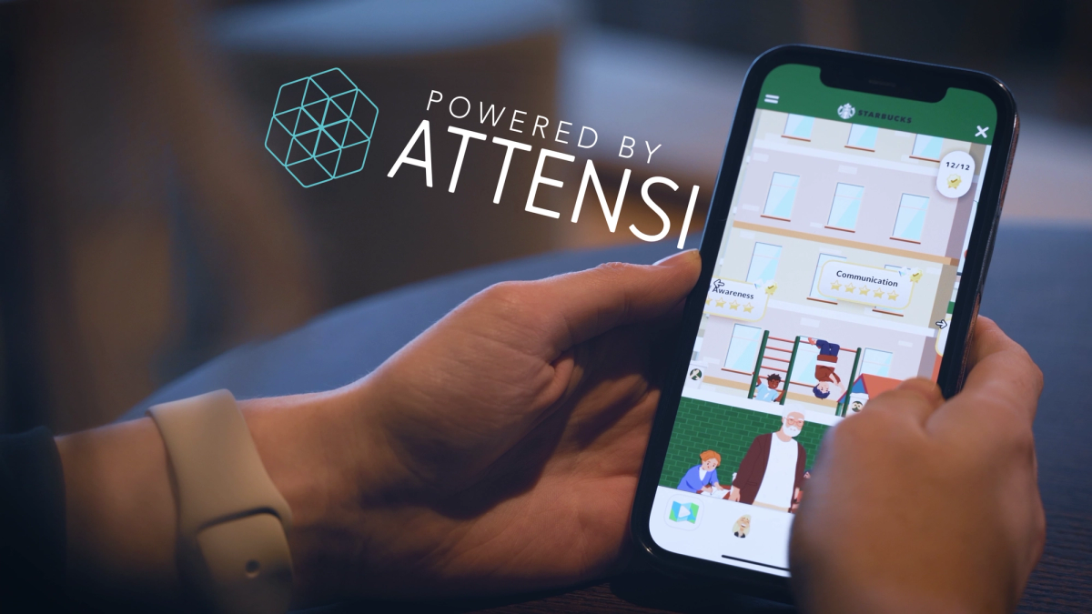 Hände halten ein Smartphone mit einer Starbucks-Kursübersicht mit den Stufen Kommunikation und Sensibilisierung, Bildunterschrift „Powered by Attensi“