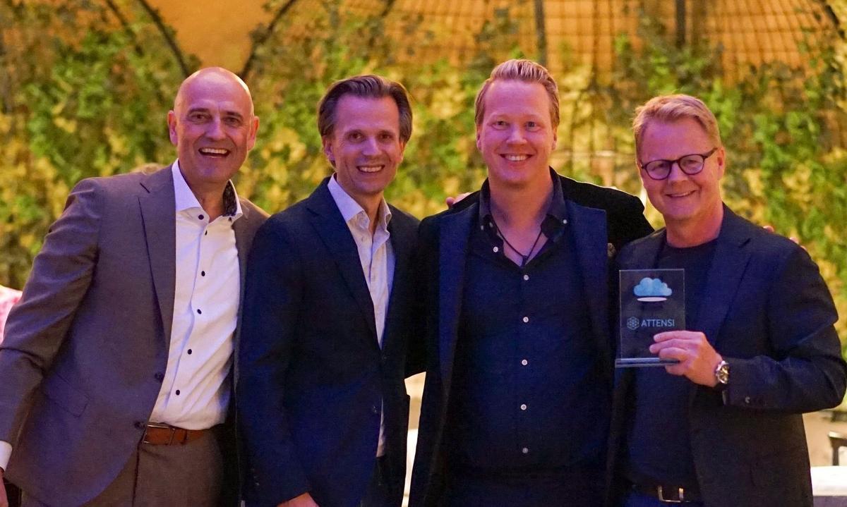 Four men smiling with an Attensi glass trophy at an awards event