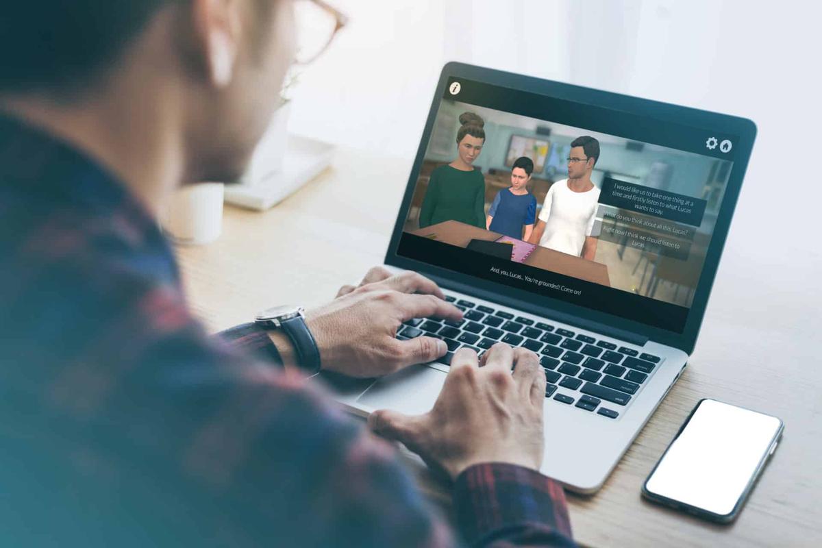 Mann am Laptop in der Talk-to-Me-Simulation, in der zwei Erwachsene und ein Kind miteinander sprechen