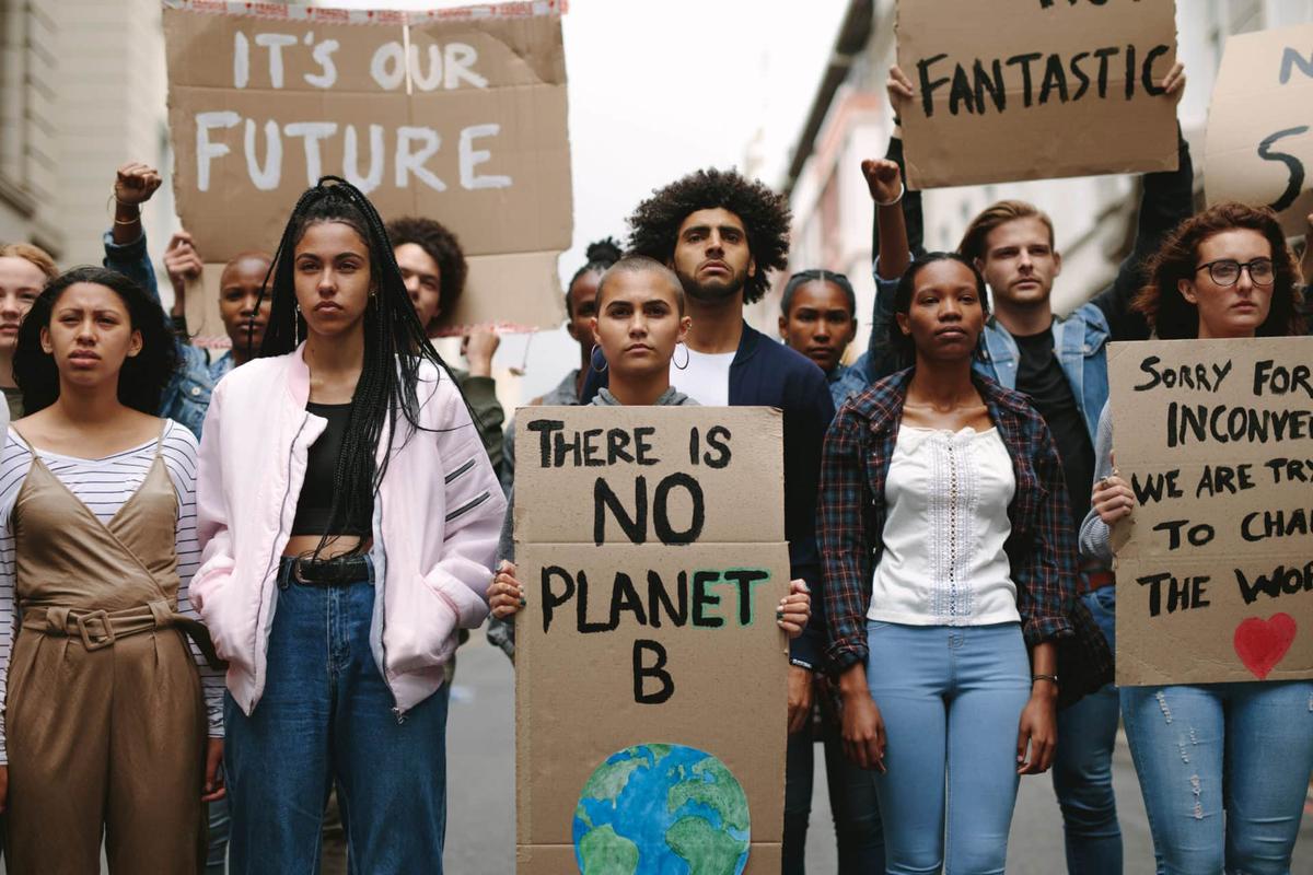 Young climate protesters holding cardboard signs reading There is no planet B and It's our future