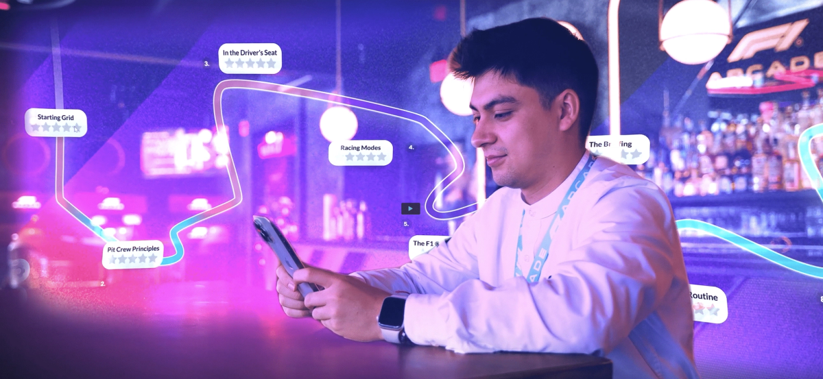 F1-Arcade-Mitarbeiter nutzt sein Smartphone an der Bar, umgeben von einer Rennstreckenkarte mit Attensi-Trainingsmodulen