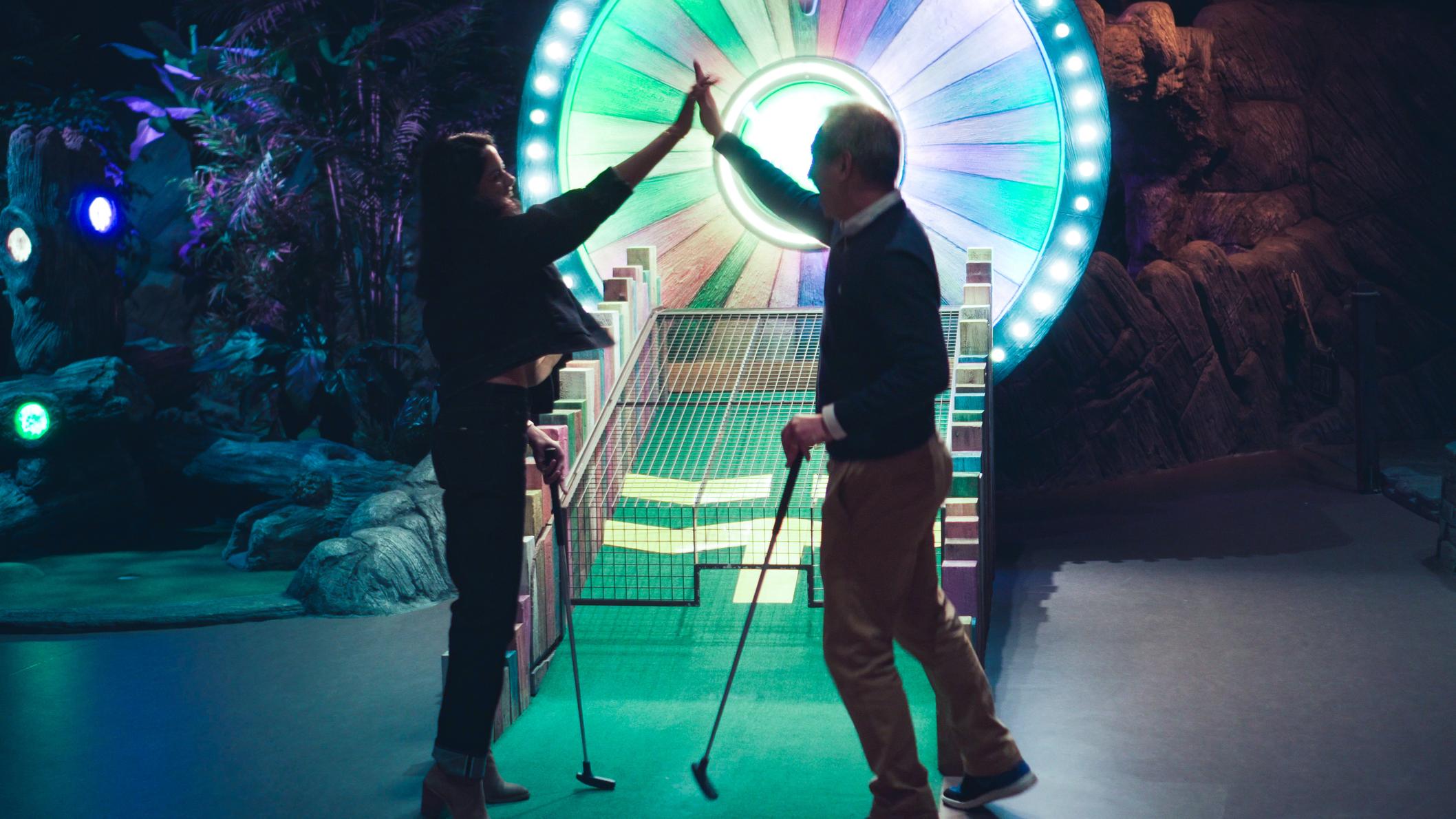 Frau und Mann spielen Minigolf in den Baumwipfeln und klatschen sich ab