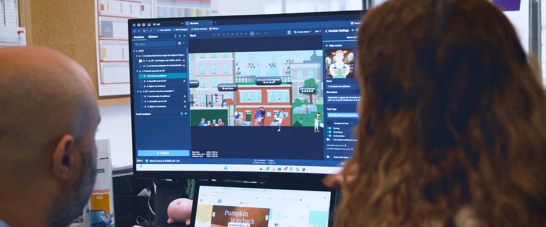 Zwei Kollegen an einem Schreibtisch betrachten am Monitor einen Trainingsmodul-Editor mit einer Spielszene eines Stores