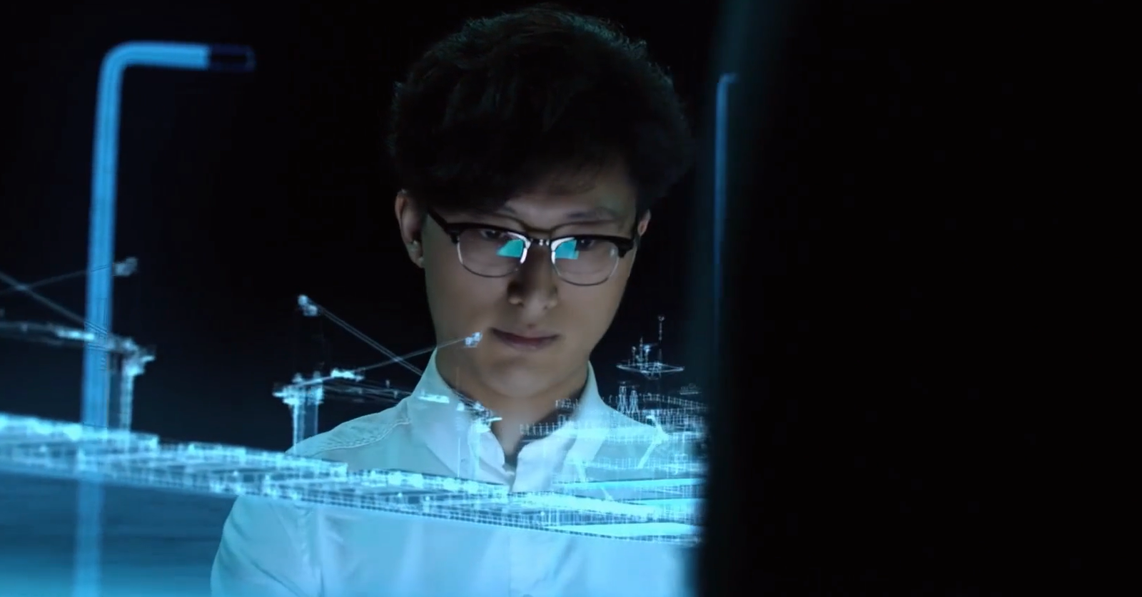 Ein Mann mit Brille betrachtet ein leuchtendes holografisches Drahtgittermodell eines Schiffs