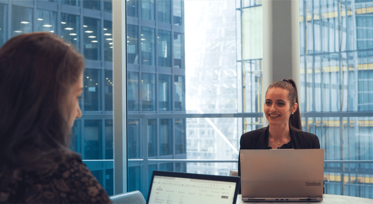 Versicherungsmitarbeitende lächeln im Büro vor ihren Computern