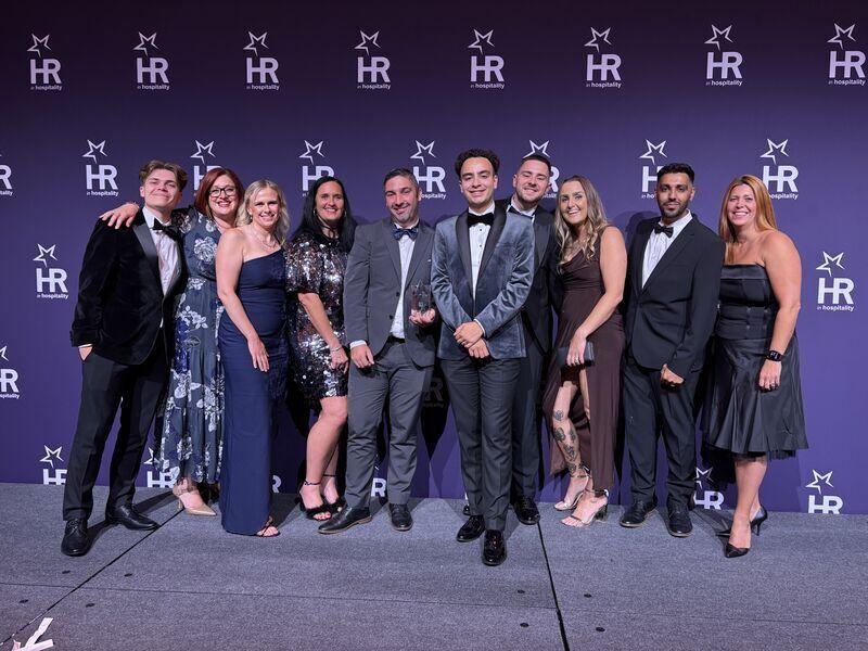 Das Welcome-Break-Team in Abendgarderobe mit seiner Auszeichnung vor der Kulisse der HR in Hospitality Awards