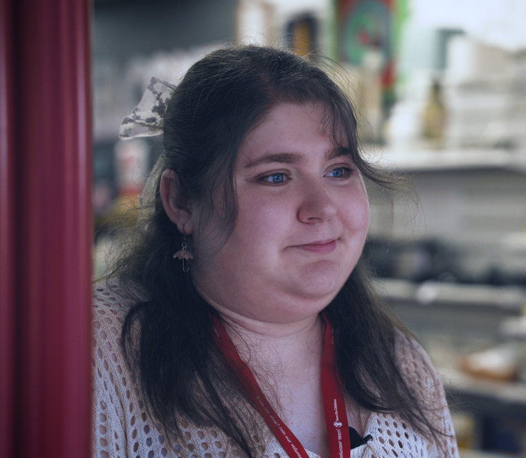 Nat trägt in einem Charity-Shop ein rotes Umhängeband