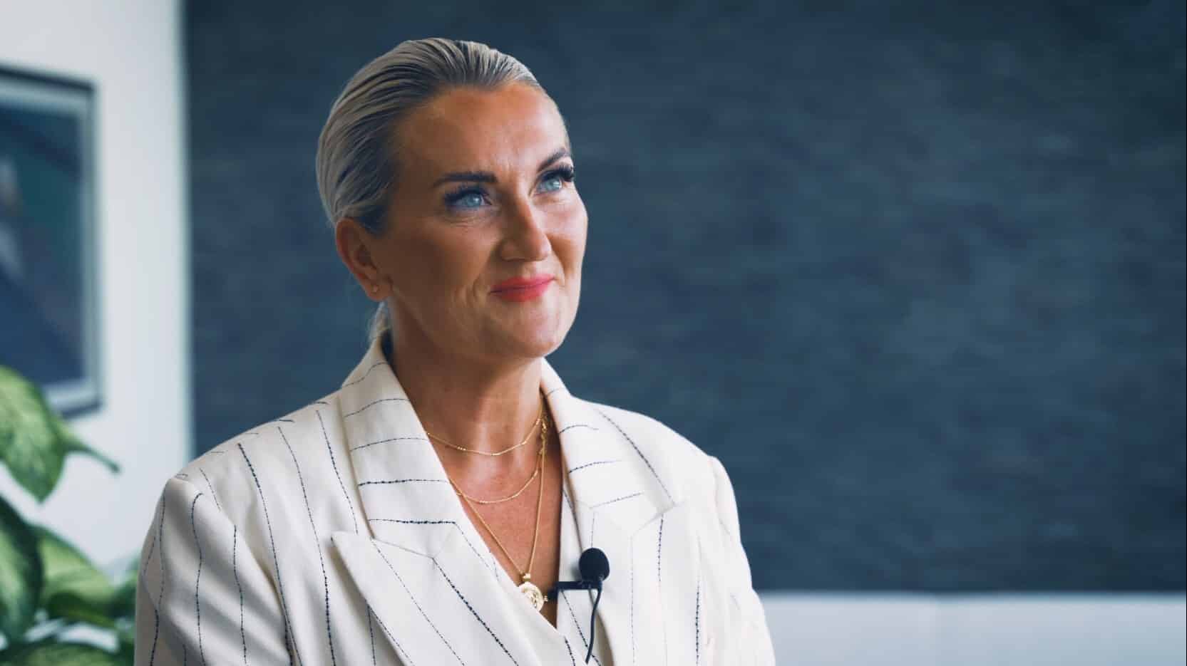 Evelyn Johnson, kvinne i hvit nålestripet blazer som snakker i et intervju