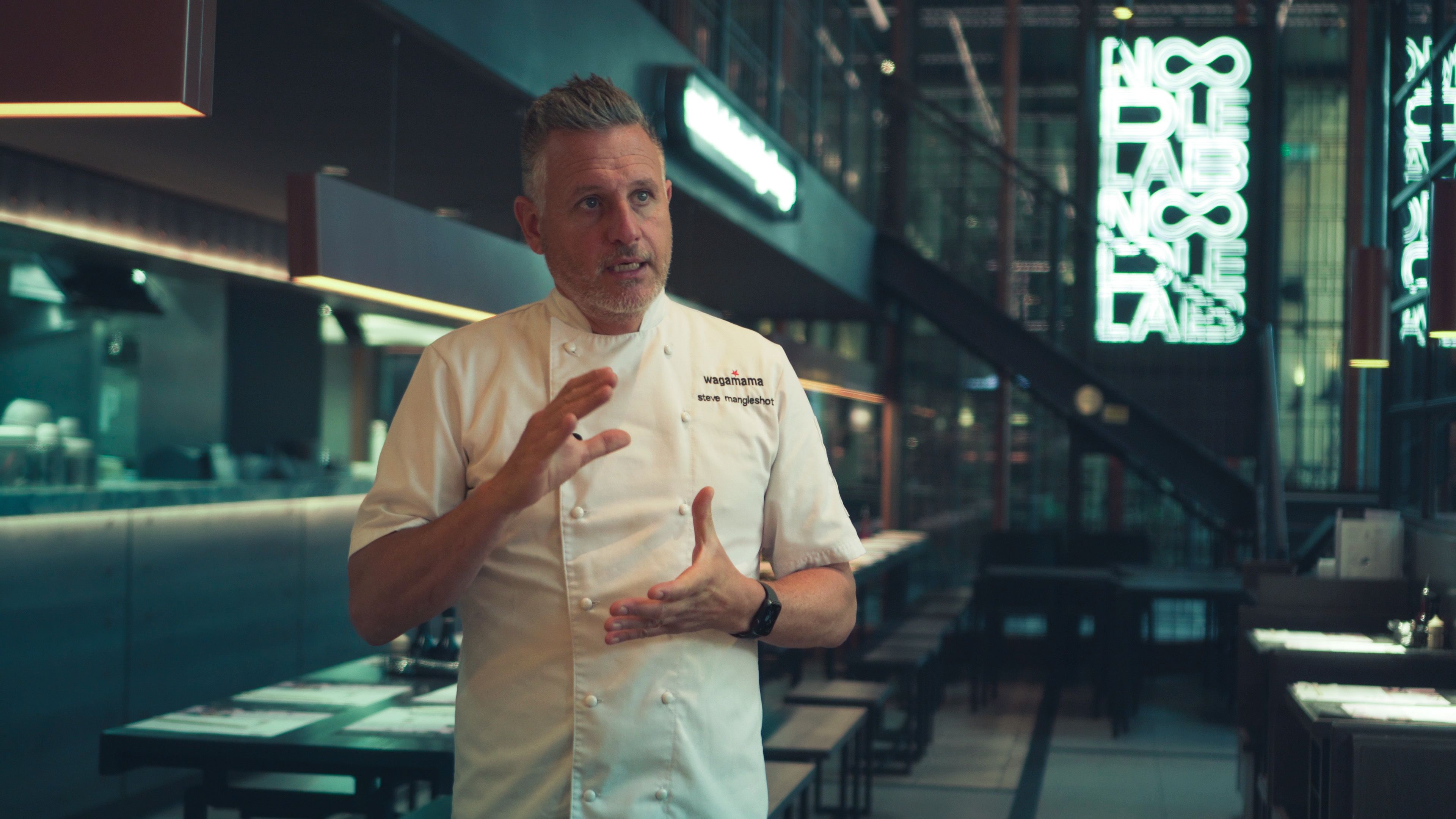 Steve Mangleshot in a wagamama chef's jacket inside a restaurant