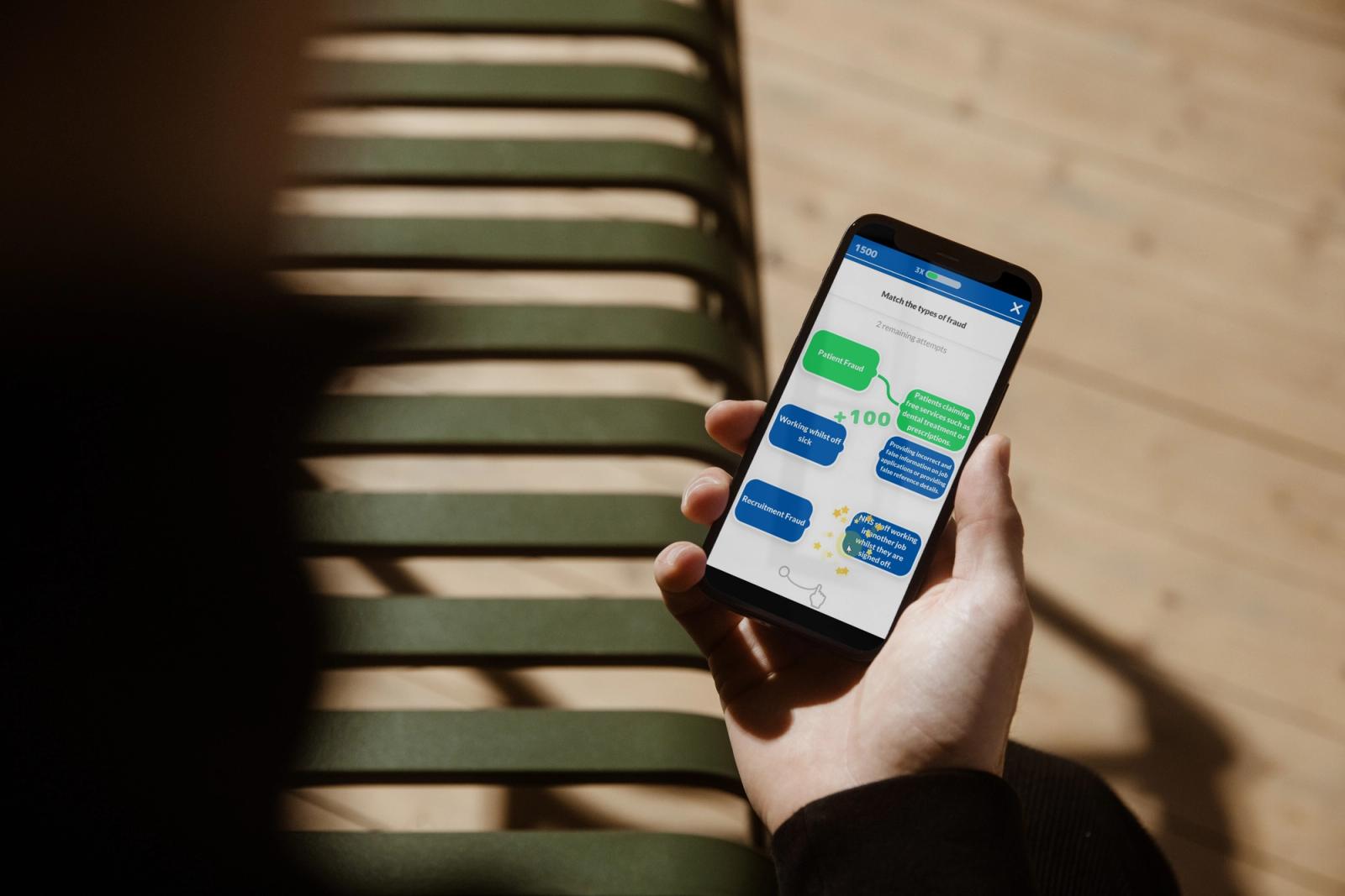 A hand holding a smartphone running a game-based training quiz that awards 100 points