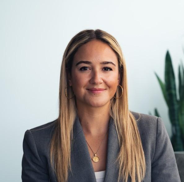 Smiling woman with long blonde hair in a grey blazer