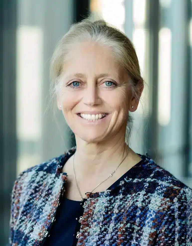 Stine Lise Hattestad Bratsberg smiling in a multicoloured tweed jacket, photographed indoors