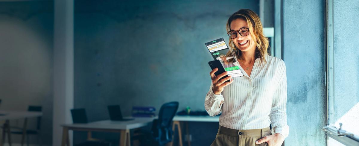 Smiling woman in glasses playing an Attensi training module on her phone in an office