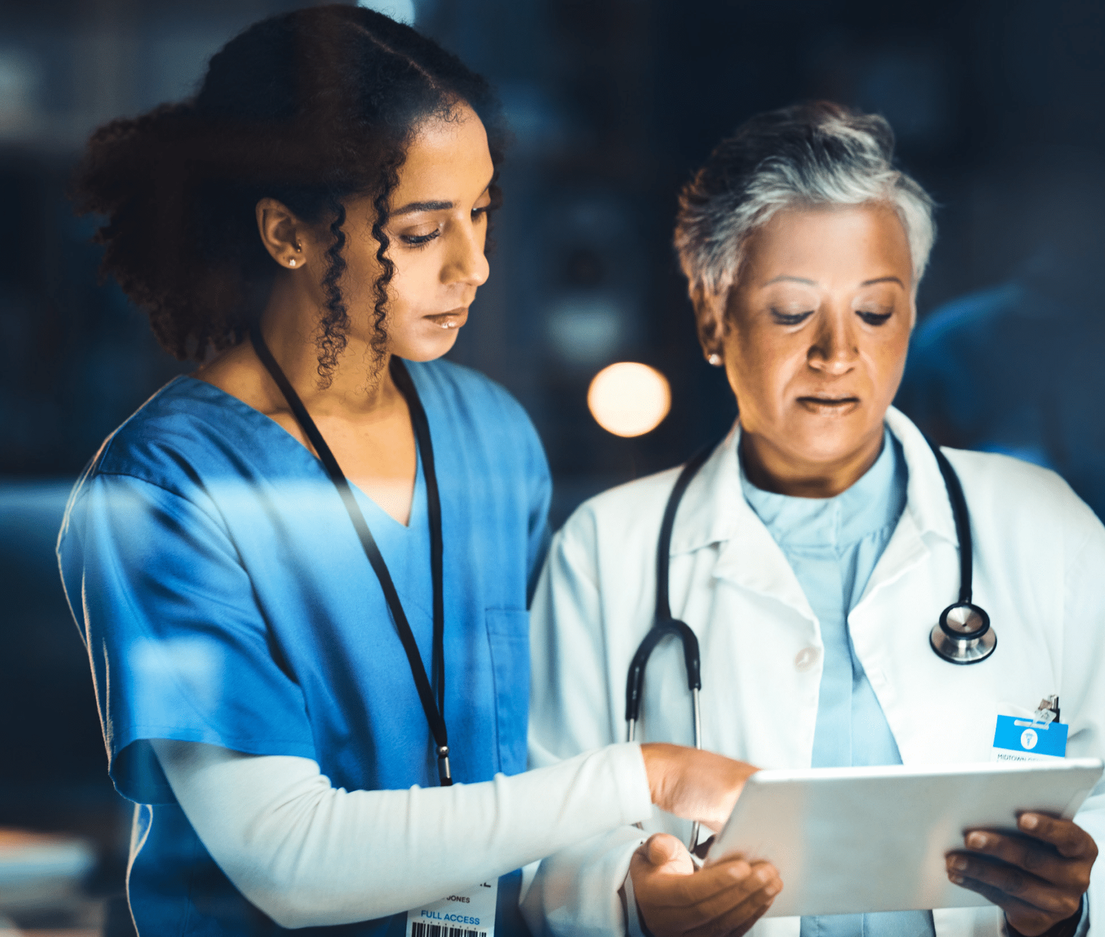 A doctor and a nurse examining a tablet.