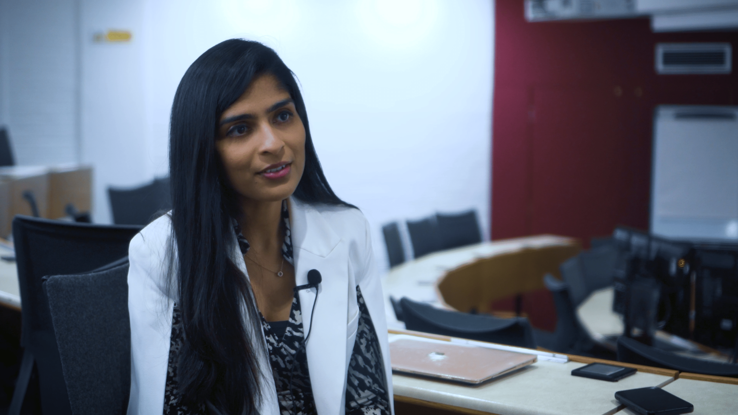 Priyal, woman in a white blazer being interviewed in a seminar room