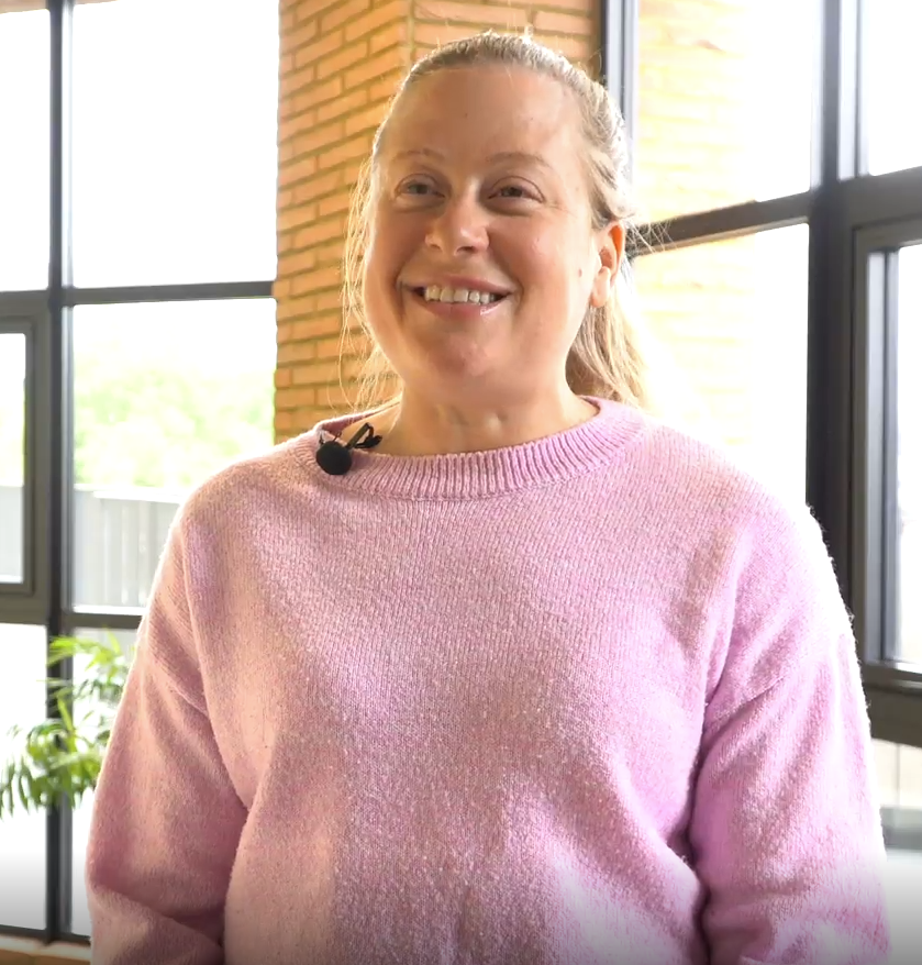 Jacy Stanhope of B&Q, smiling in a pink jumper in front of tall windows