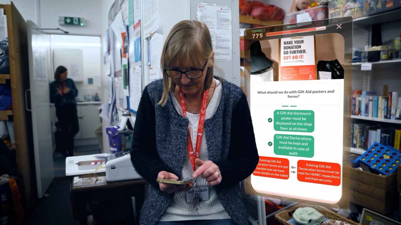 Woman on her phone in a stockroom beside an enlarged quiz screen about Gift Aid posters and forms